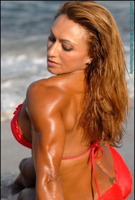 Bodybuilder Karina Nascimento flexes on a beach while wearing a red bikini 43092459